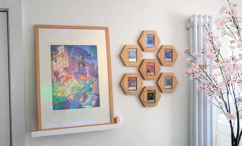 Trading cards in hexagonal frames on a white wall next to a large art peice